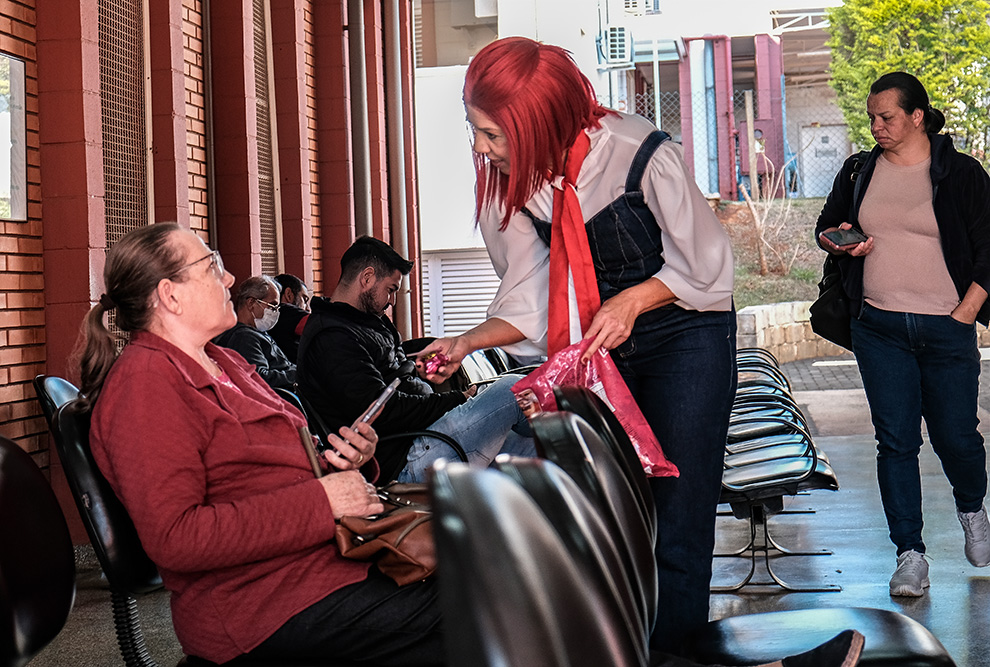 À esquerda, personagem Maria Clot distribui brindes para pacientes; à direita os professores da FCM Joyce Maria Annichino e Erich Vinicius de Paula 